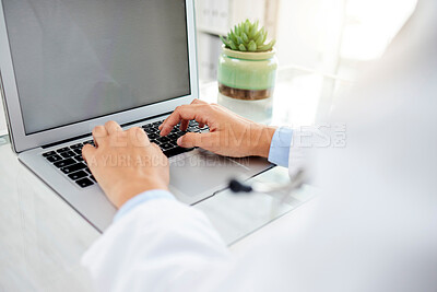 Buy stock photo Unknown mixed race woman using a laptop and typing a email while sitting at her desk in a hospital. Female doctor using a wireless device while working