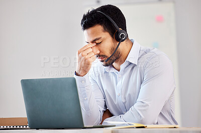 Buy stock photo Young mixed race man looking stressed while working as a call centre agent. Handsome man suffering from depression and a headache while wearing a headset and working in an office job 
