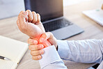 Closeup of hand and wrist pain highlighted in red. A businessman holding his arm with an injury. Male employee working at his desk in a modern office and suffering from a medical problem