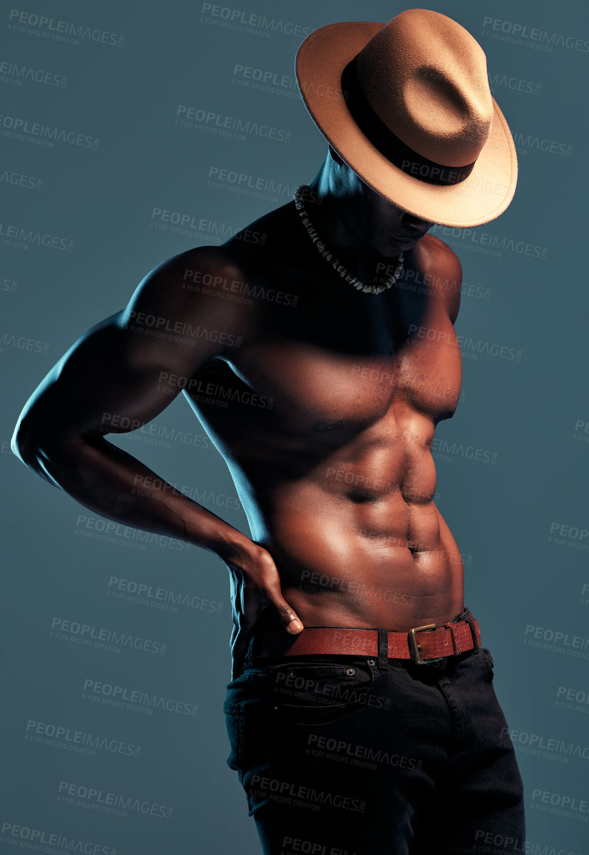 Buy stock photo Black man, topless and sexy fashion model with abs, cow boy style with hat isolated on blue background. Dark, shadow and body with muscular male person, pose with six pack and stylish in studio