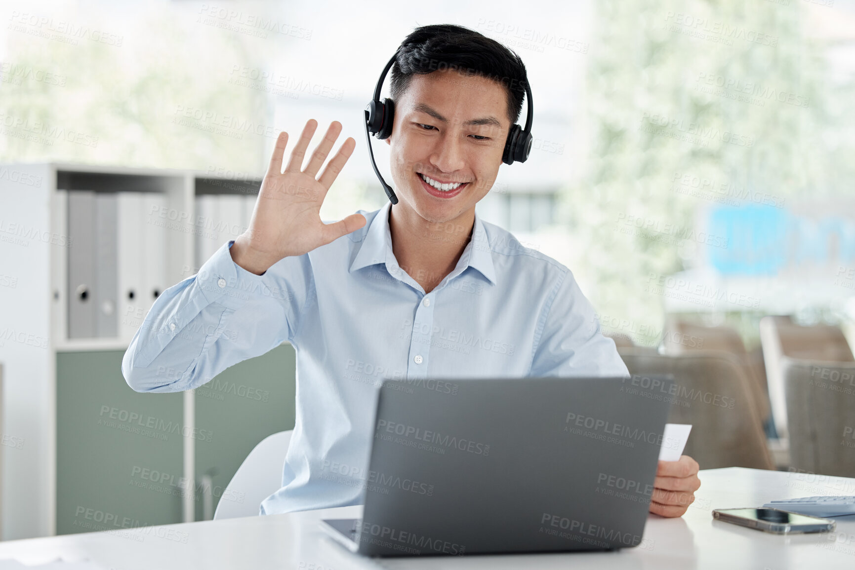 Buy stock photo Asian man, laptop and video call in call center, customer service or virtual assistant at the office. Happy male person or consultant agent waving hello on computer for online advice at the workplace