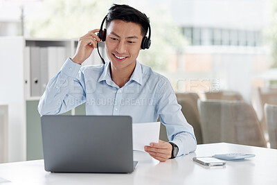 One young asian call centre agent talking on headset while reading document with laptop in office. Salesman and marketing rep consultant advising while operating help desk for customer service support