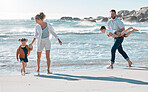 Carefree caucasian family walking and having fun together on the beach. Parents spending time with their son and daughter while on holiday. Little siblings playing with their parents on vacation