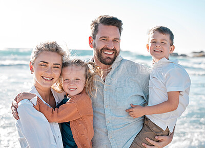 Buy stock photo Portrait of happy caucasian parents and kids sharing quality time while enjoying a fun family summer vacation at the beach. Loving mom and dad holding and bonding with their little son and daughter