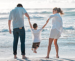 Cheerful caucasian family walking on the beach. Happy family with tone child only having fun at the beach during summer vacation. Child enjoying a getaway with his parents on bright summer day