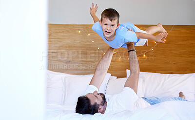 Buy stock photo Caucasian father lifting his cute little son in the air to pretend to fly like a plane or superhero with arms out on a bed at home. Loving dad playing and bonding with cheerful kid in the morning