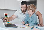 Young caucasian father helping his son with homework at home. Little boy and dad using a laptop and writing in a notebook together at home. Parent showing a child how to draw at home