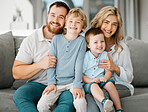 Portrait of a happy caucasian family looking relaxed while bonding on a sofa together. Adorable little boys chilling on a couch with their loving parents while smiling and looking positive
