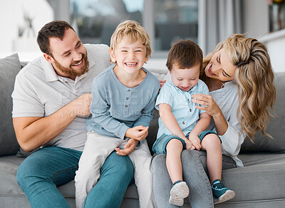 Carefree loving parents tickling and bonding with cute little laughing sons. Smiling caucasian family of four relaxing on the sofa at home.Playful young boys spending quality time with mom and dad