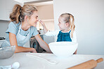 Little girl baking with her mother. Mother and daughter bonding while cooking. Little child playfully putting flour on her moms nose. Happy mother and child playing while baking together