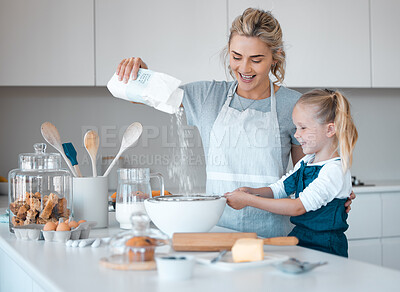 Mother helping her daughter sift flour into a bowl. Happy mother and daughter baking in the kitchen.Caucasian little girl baking with her mother.Small child using a sieve to sift flour into a bowl