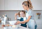 Portrait of a little girl baking with her mother. Happy mother helping her daughter bake. Parent baking with her child in the kitchen.Mother helping her daughter bake at the kitchen counter.