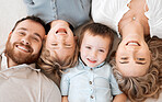 Faces of happy caucasian family from above. Top view portrait of cheerful young family with two sons lying together while looking up at camera. Married couple with children