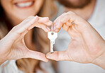 Closeup of newlywed caucasian couple making heart shape with hands and holding house key to move into new apartment. Relocating after buying first home and securing loan for property or real estate
