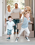 Happy family moving into new house. Excited children running into their new house. Family carrying boxes, moving into their house. Happy caucasian family walking into new purchased property.