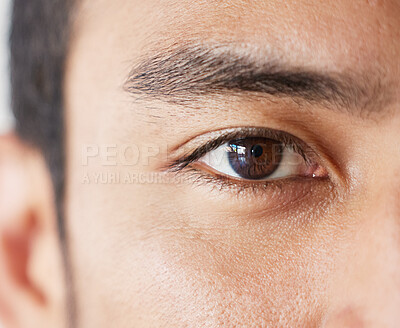 Closeup eye of mixed race male looking serious in studio. Asian male standing indoors with no expression and copyspace. Ready to see the optometrist for his eye checkup and medical exam