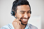 Closeup of smiling mixed race call centre agent smiling while wearing headset. Young male customer service representative using wireless headset and consulting clients online