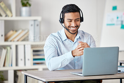 Closeup of smiling mixed race call centre agent smiling while wearing headset. Young male customer service representative using wireless headset and consulting clients online while using a laptop