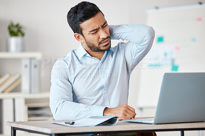 Exhausted business man holding sore neck while sitting at desk with laptop. Overworked professional suffering from neck pain or strain