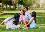 Portrait of happy asian couple lying together on grass. Kids playing while watching their loving parents spending time together at the park