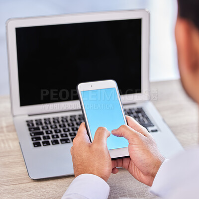 Closeup hand of businessman using smartphone. Businessman typing on blue blank screen mobile phone mockup and browsing internet on laptop. Linking devices doing data transfer, using cloud storage