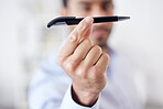 Closeup of a mixed race businessman holding a pen in the foreground while standing in the office at his job