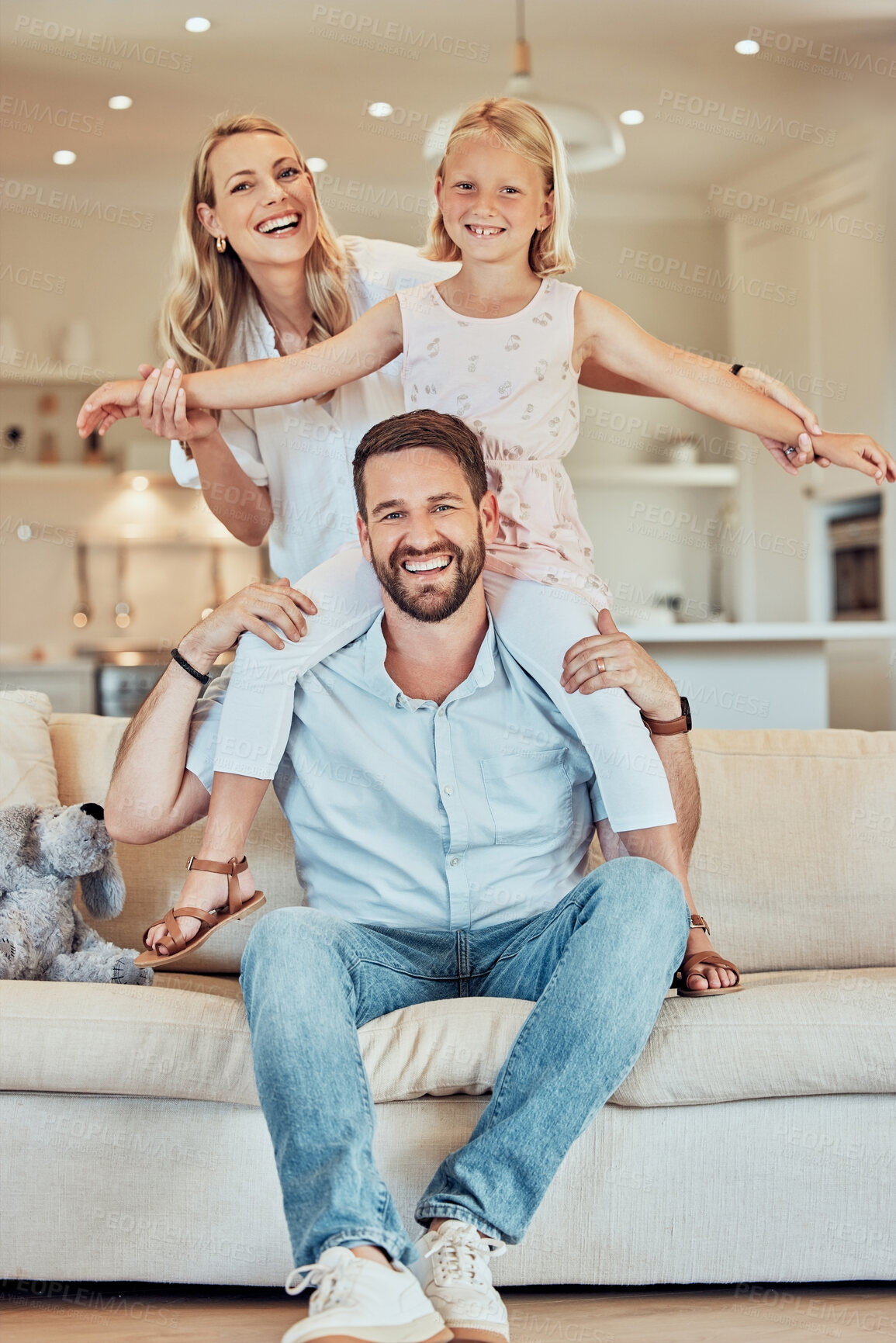Buy stock photo Portrait of excited little playful girl sitting on father's shoulders and holding mother's hands while pretending to fly at home. Happy caucasian parents enjoying fun quality time with daughter