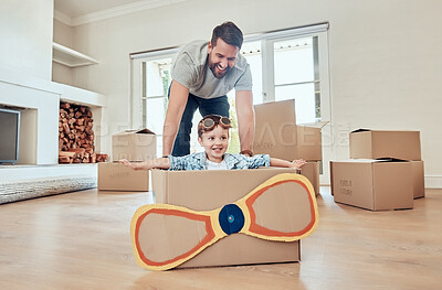 Buy stock photo Happy single father pushing his little kid in homemade aeroplane cardboard box at home. Adorable little boy sitting in makeshift plane and playing with single parent in a living room in their new home