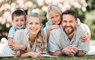 Buy stock photo Young happy caucasian family relaxing and lying on grass together in a park. Loving parents spending time with their son and daughter in nature. Joyful siblings hugging their mom and dad outside