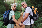 Portrait of a mature couple holding hands while out hiking together. Senior couple smiling during a hike  looking happy in nature