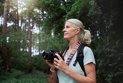 A mature caucasian woman taking pictures with her camera while out hiking. Senior female using her wireless digital camera to take photos in nature during a hike outdoors