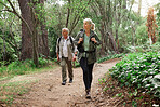 A mature caucasian couple out for a hike together. Senior man and woman smiling and walking in a forest in nature