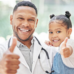 Doctor and child patient showing thumbs up. Portrait of handsome young black paediatrician holding adorable little girl in hands, cute child and doctor smiling during medical check up in clinic