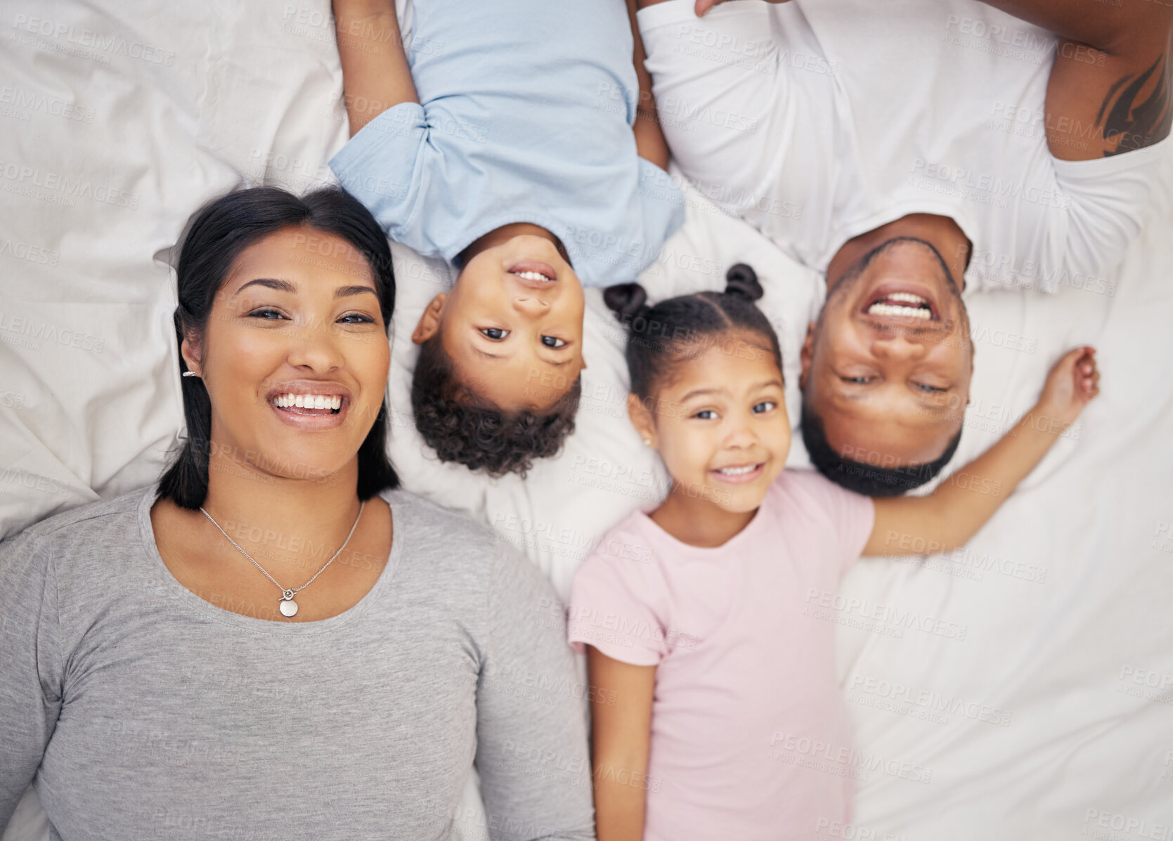 Buy stock photo Happy mixed race family relaxing together and bonding at home from above. Little brother and sister spending time with their parents