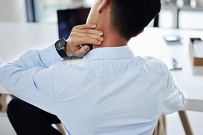 Rear view of a businessman experiencing discomfort while sitting at his desk. Unknown male suffering on neck pain while sitting at the desk in a office