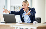 A young caucasian businesswoman yelling while using a laptop in an office at work. Female having a stressful day at work and showing her frustration