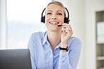 Portrait of young caucasian female call centre agent talking on headset while working on computer in an office. Confident and happy businesswoman consulting and operating a helpdesk for customer sales and service support