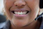 Closeup of one happy african american call centre telemarketing agent with big smile talking on headset while working in office. Face of confident friendly businesswoman operating helpdesk for customer service and sales support