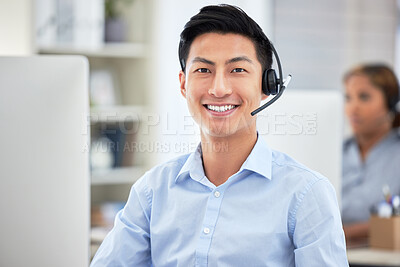 Portrait of asian call centre agent talking on headset while working on computer in office. Confident and smiling businessman consulting and operating a helpdesk for customer sales and service support