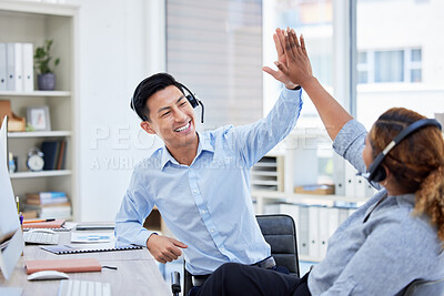 Two young happy male and female call center agents giving each other a high five answering calls working in an office. Cheerful Chinese and hispanic businesspeople joining hands celebrating success