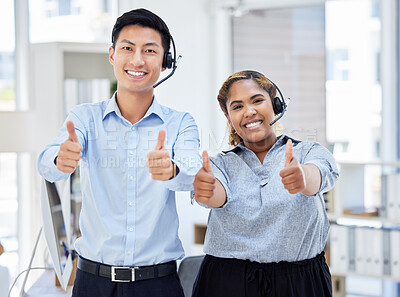 Two young happy male and female call center agents showing thumbs up while answering calls working in an office at work. Pleased asian man and mixed race woman customer service workers showing support