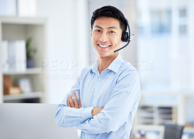 Portrait of asian call centre agent wearing a headset while working in office while stand with arms crossed . Confident and smiling businessman consulting and operating a helpdesk for customer sales and service support