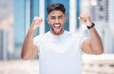 Young mixed race male athlete celebrating a goal, making a winner gesture with clenched fists after a run in the city. Cheerful fit man celebrating while exercising outdoors