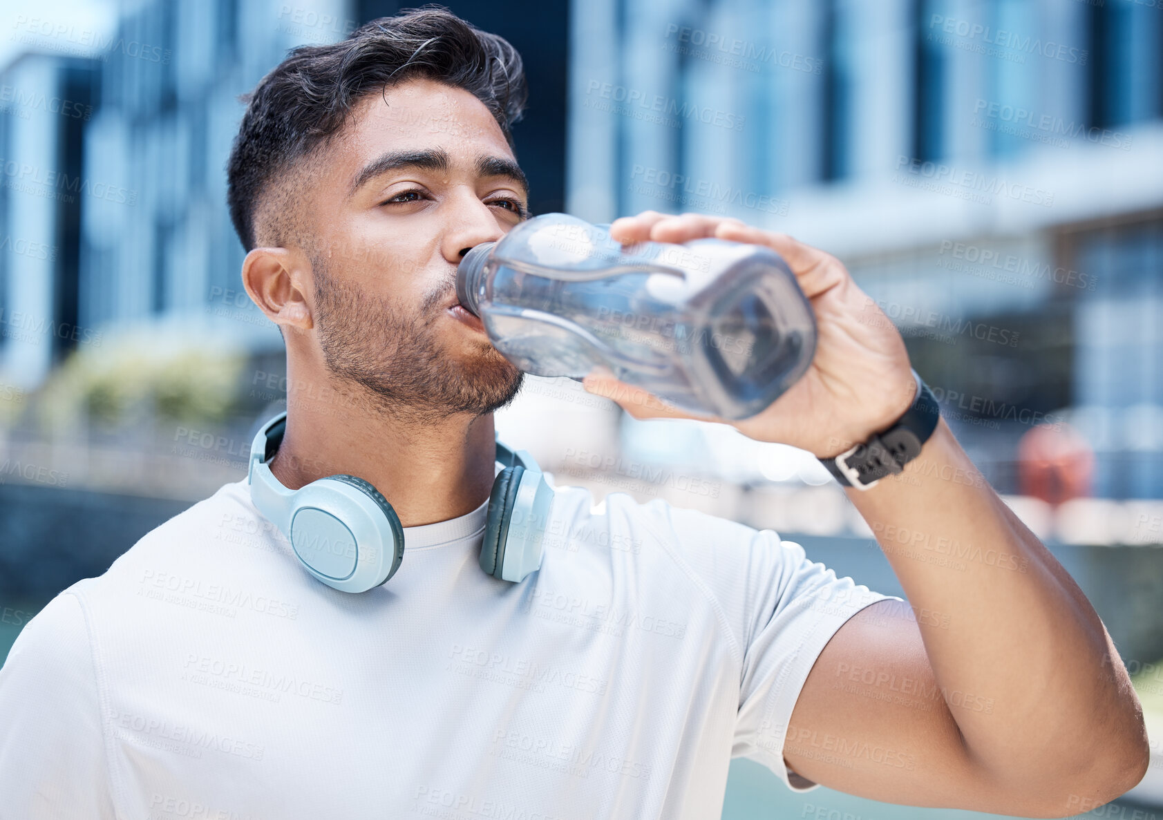 Buy stock photo Man, fitness and drinking water in city after exercise, cardio workout or training outdoors. Thirsty male person, athlete or runner with drink for hydration, rest or break from run in an urban town