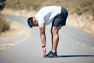 Fit young mixed race man stretching before his exercise outdoors. Handsome indian male warming up and getting ready in preparation for a run or jog outside in nature. Endurance and cardio training