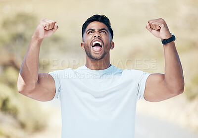 Closeup of a young mixed race man celebrating while out for a workout. Indian male looking ecstatic and cheering outside after a workout in nature