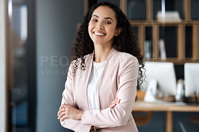 Portrait of a happy mixed race businesswoman standing with her arms crossed alone in her office. One hispanic professional feeling confident standing at work. Female boss working as an entrepreneur