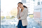 Young unhappy mixed race businesswoman suffering from a headache standing in an office. One tired hispanic businessperson suffering from burnout standing at a window at work