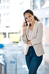 Portrait of a happy mixed race businesswoman on a call using her phone in her office. One hispanic businesswoman feeling confident standing and talking on her cellphone at work