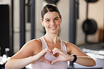 Portrait of smiling caucasian athlete showing heart shape sign and symbol during workout in gym. Strong, fit, active woman showing passion and love for exercise and training in health and sports club